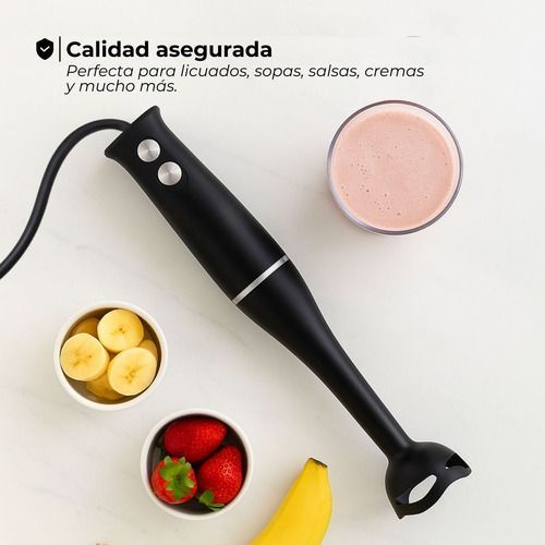 Batidora de mano negra con ingredientes para frutas y sopa sobre un fondo blanco.