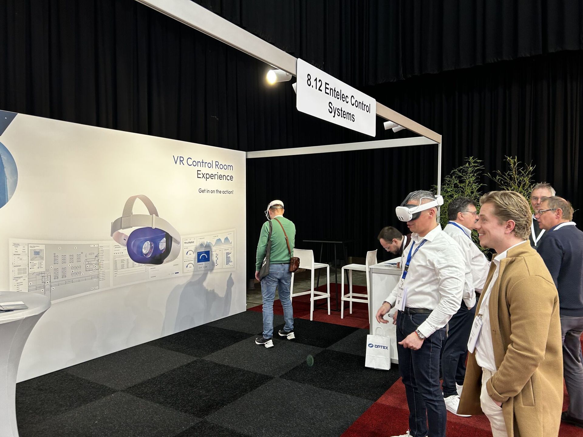 People at a VR display booth of Entelec , some wearing headsets. Signage for 