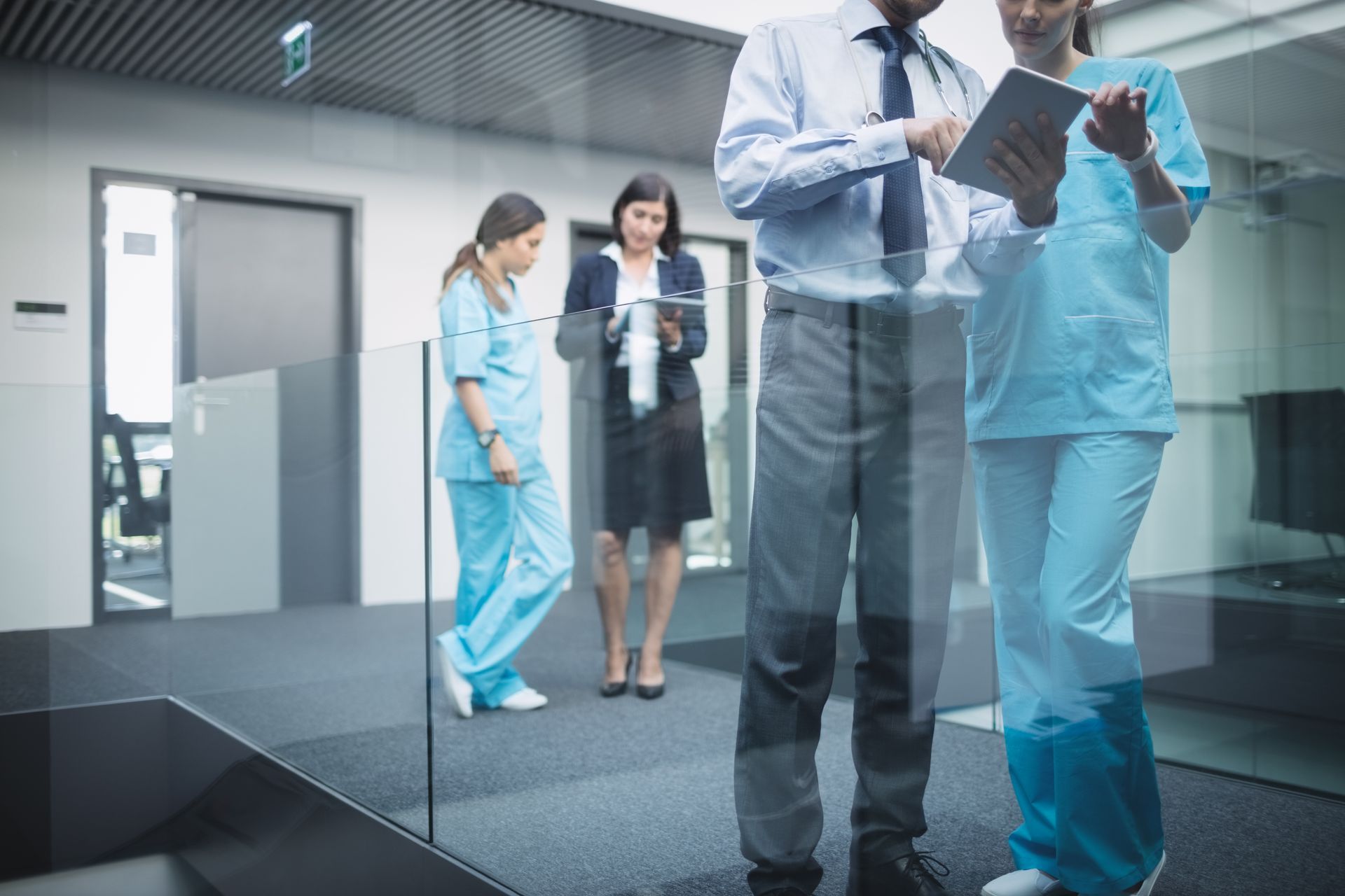 Discover the power of PSIM in healthcare facilities Doctors standing in hospital corridor using portable healthcare technology