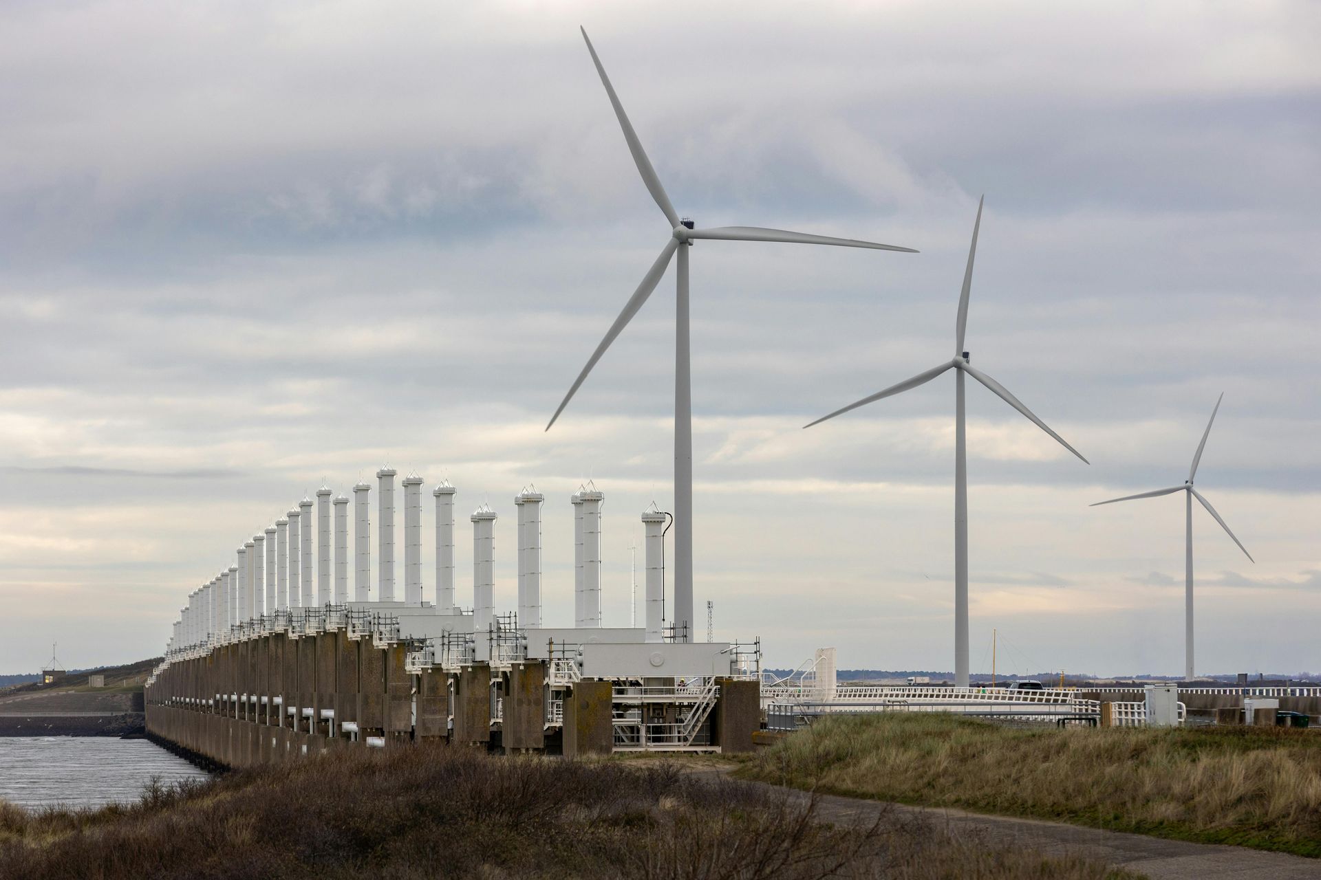 Three wind turbines stand next to the Oosterscheldekering storm surge barrier.  Sky-Walker