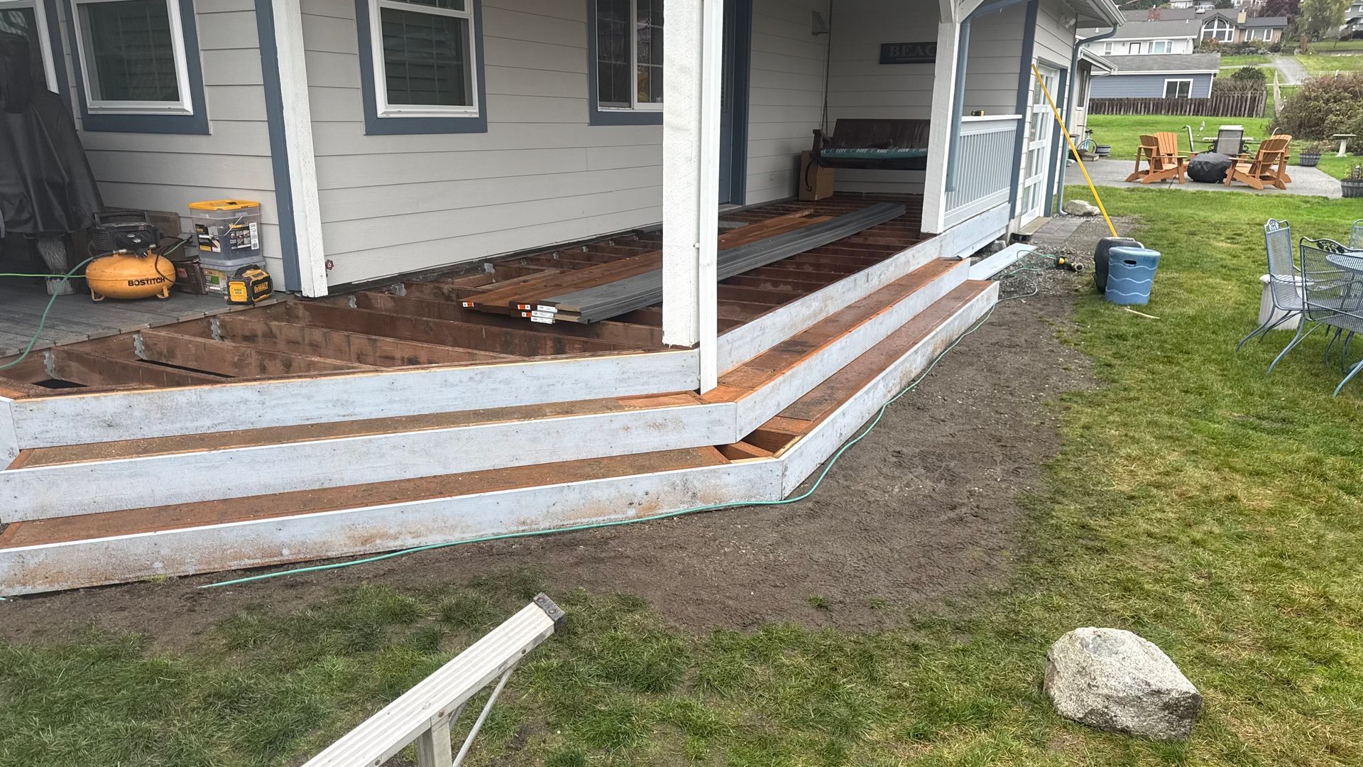 House porch with white trim and brown steps, showing fresh landscaping and a grassy yard.