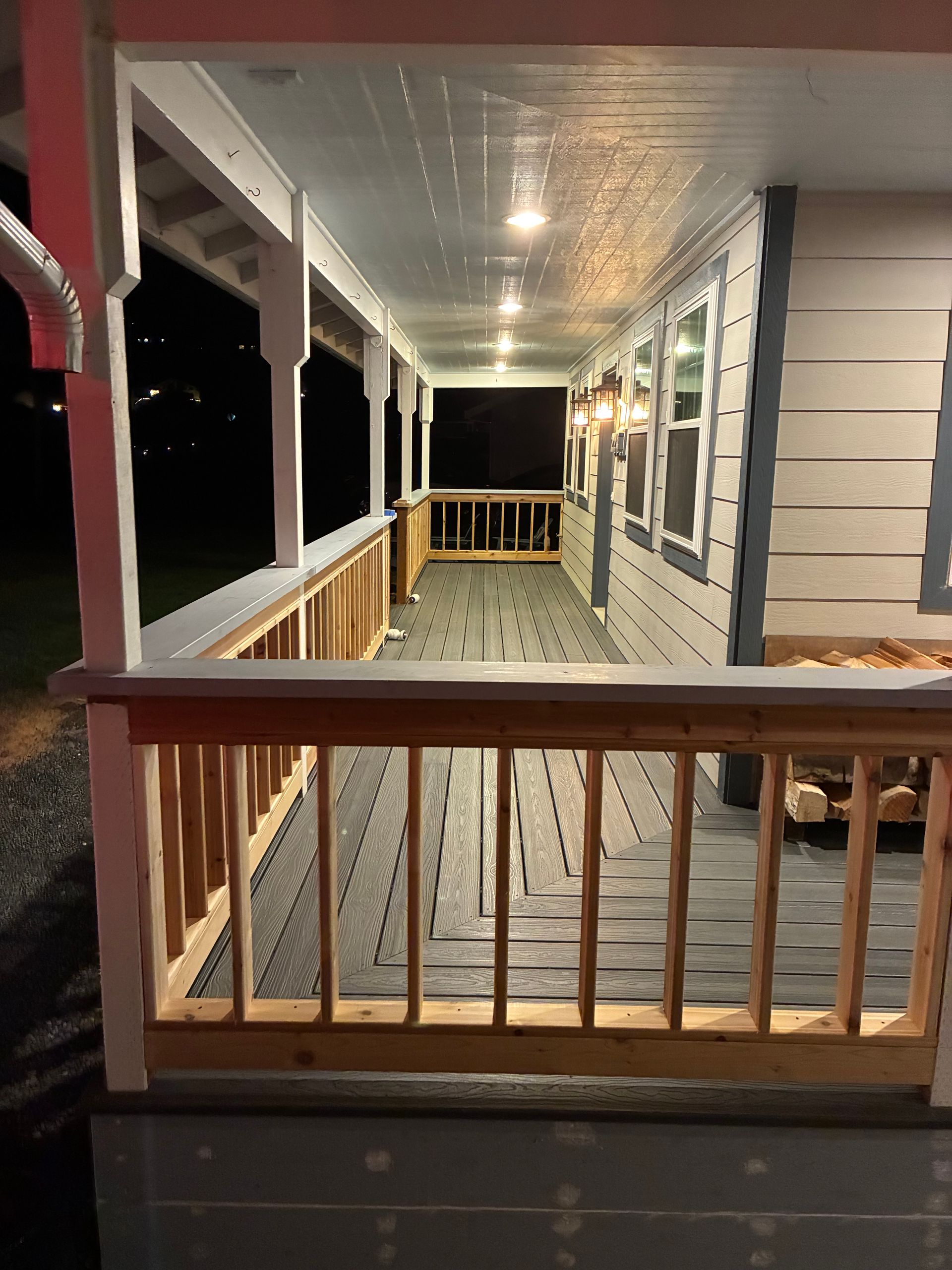 Porch with white railings, red trim, and rocking chairs at night, viewed from the front steps
