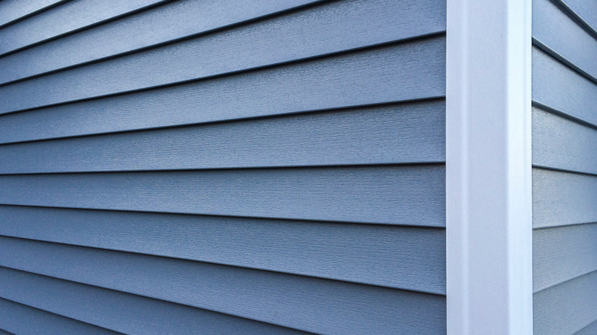 Close-up of blue horizontal house siding with a white corner trim