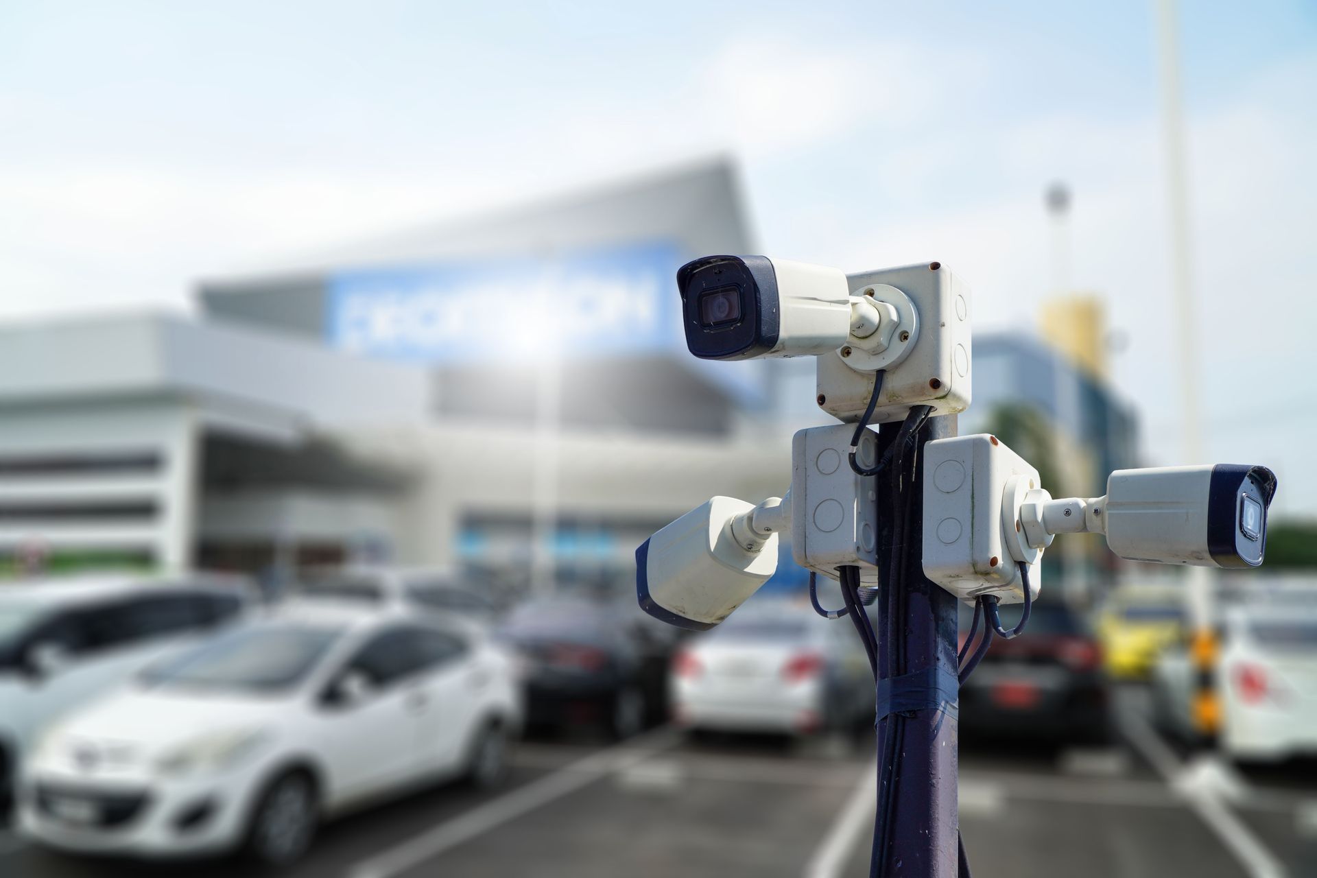 Several CCTV cameras are installed on the same pole in a parking lot