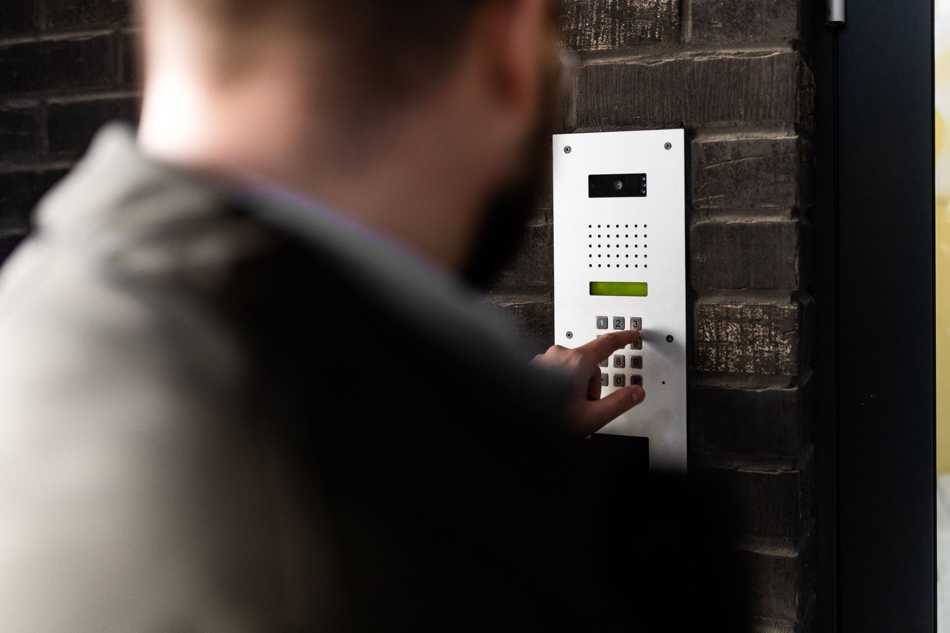 Individual activating an intercom, highlighting functionality in access control systems.