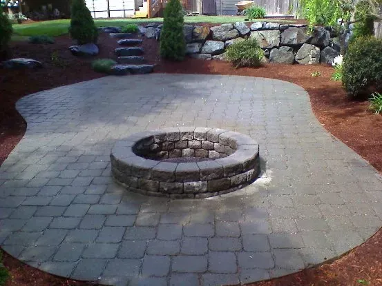 A fire pit is sitting on top of a brick patio.