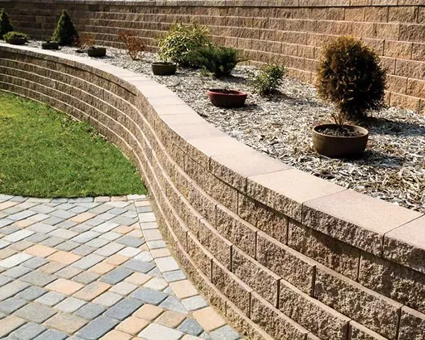 A brick wall surrounds a lush green lawn and a brick walkway.