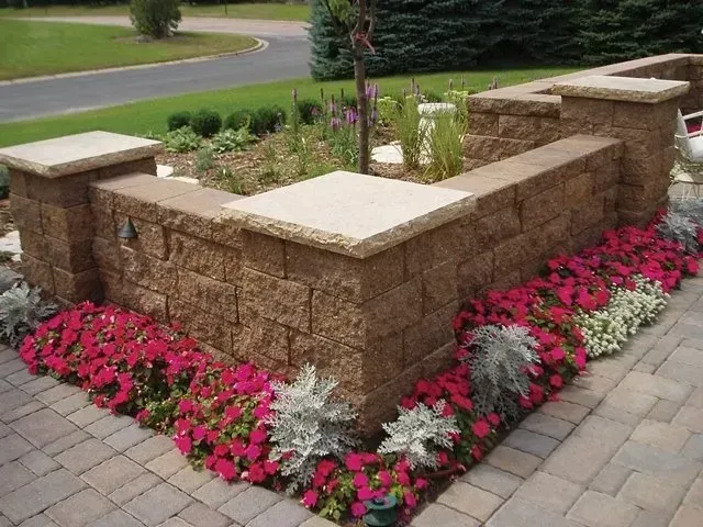 A brick wall surrounded by pink and white flowers