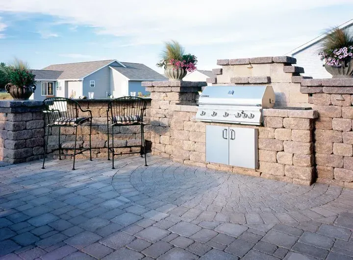 A grill is built into a stone wall on a patio.