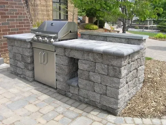 An outdoor grill is built into a brick wall