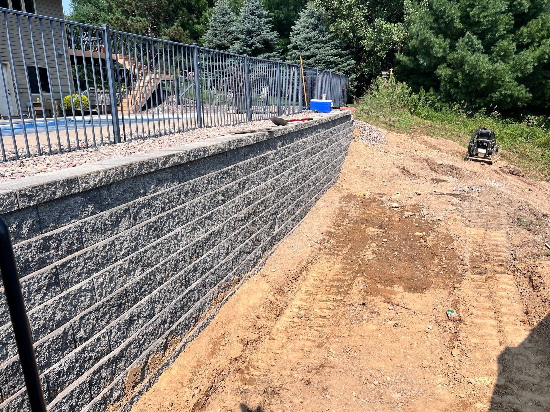 A large brick wall is being built next to a pool.