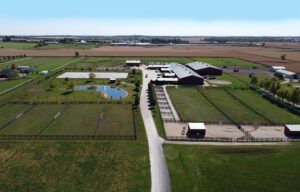 Aerial view of a rural farm with fields, dirt roads, and barns under a clear sky