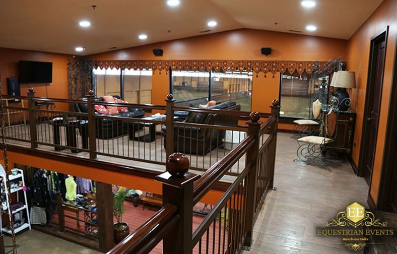 Warm-toned loft interior with wooden railings, recessed lights, and a pool table in the background