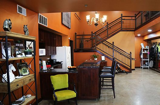 Orange lobby with wooden staircase, reception desk, shelves, and seating area