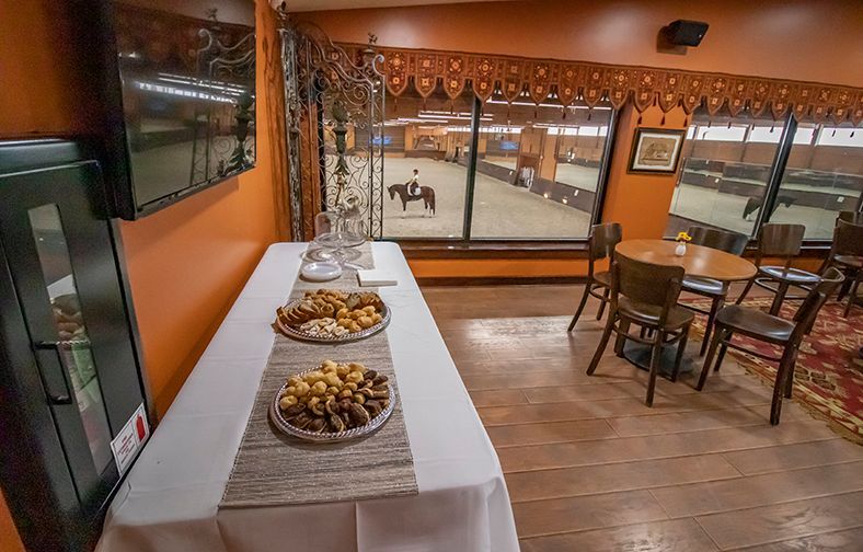 Dining room with buffet table of snacks, wooden floor, and large windows overlooking the outside.
