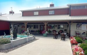 Courtyard patio with fountain, potted plants, outdoor tables, and flower beds beside a building