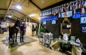 Indoor market stall with hanging textiles, lit counter, and two people standing on a wooden floor