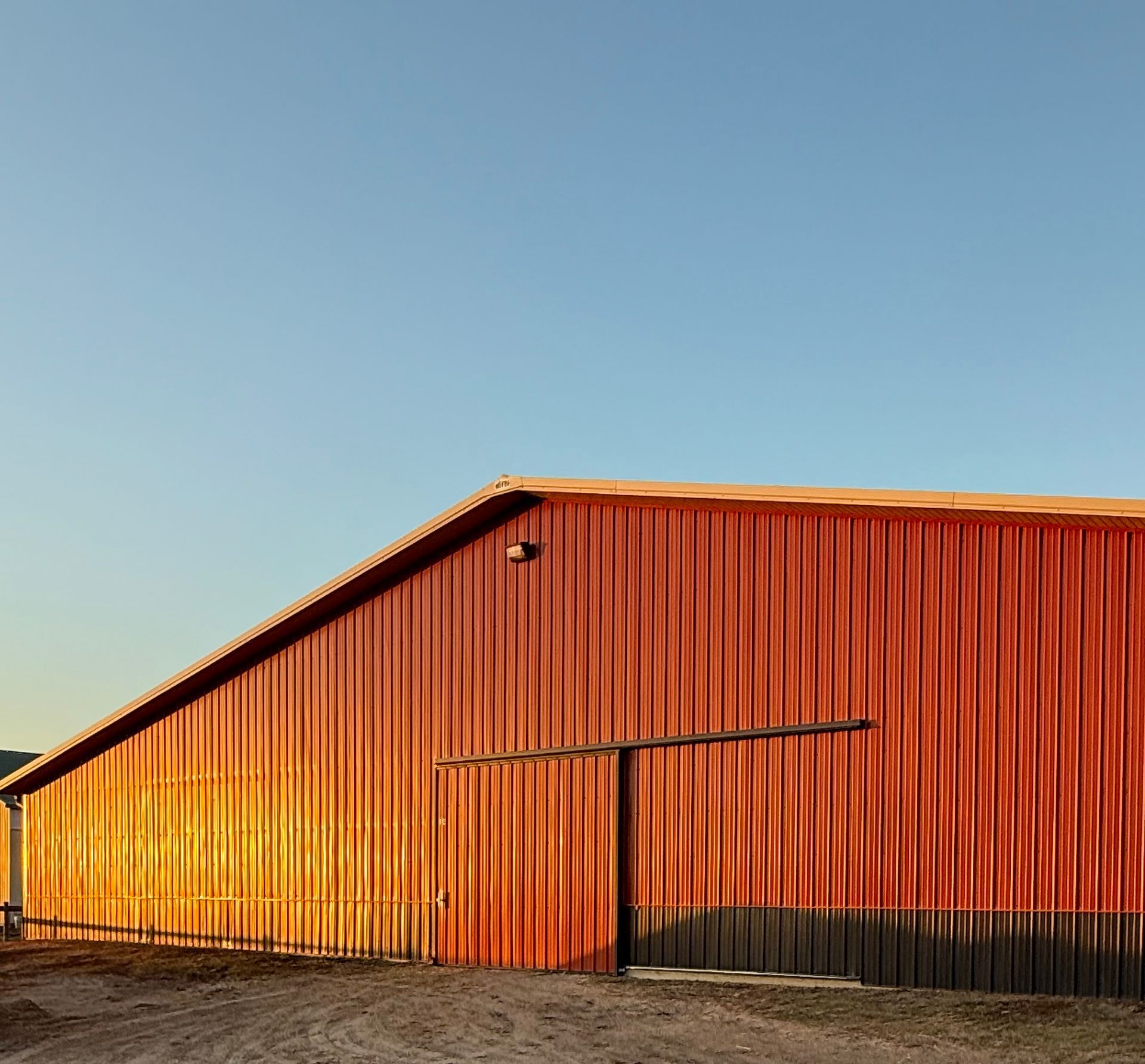 Orange metal warehouse under a clear blue sky at sunset