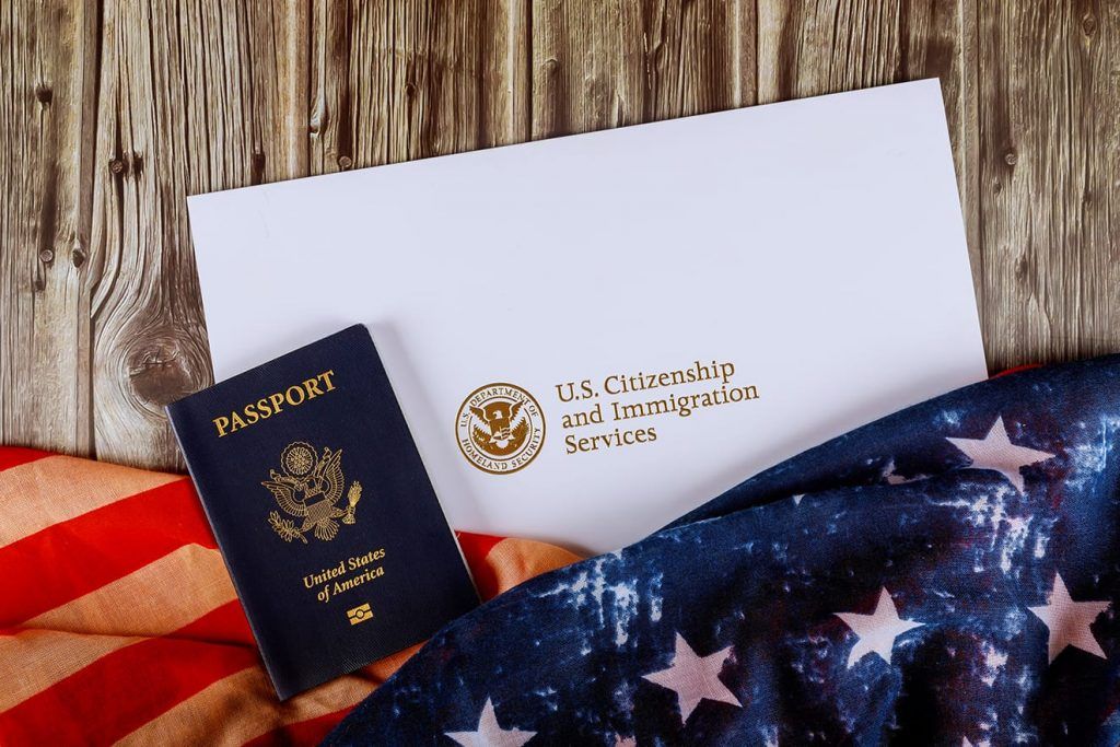 U.S. passport, envelope, and American flag on a wooden surface