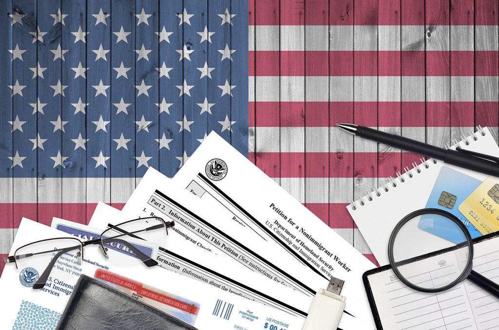 Scattered tax forms, calculator, and glasses in front of a U.S. flag background