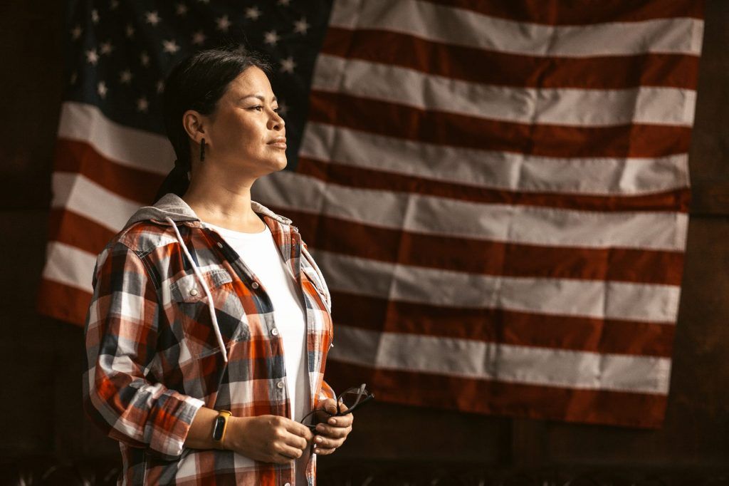 Person holding an American flag in front of a large U.S. flag backdrop.