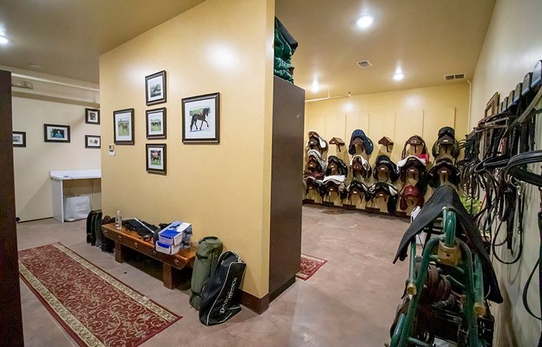 Hallway with framed photos, boots, and riding gear neatly organized on both sides
