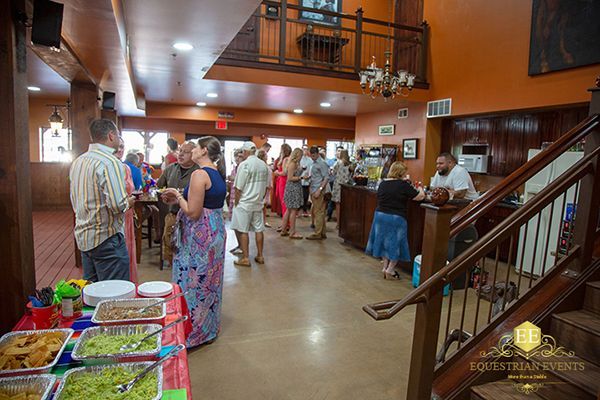 Crowded buffet hall with people waiting in line near food stations and a staircase