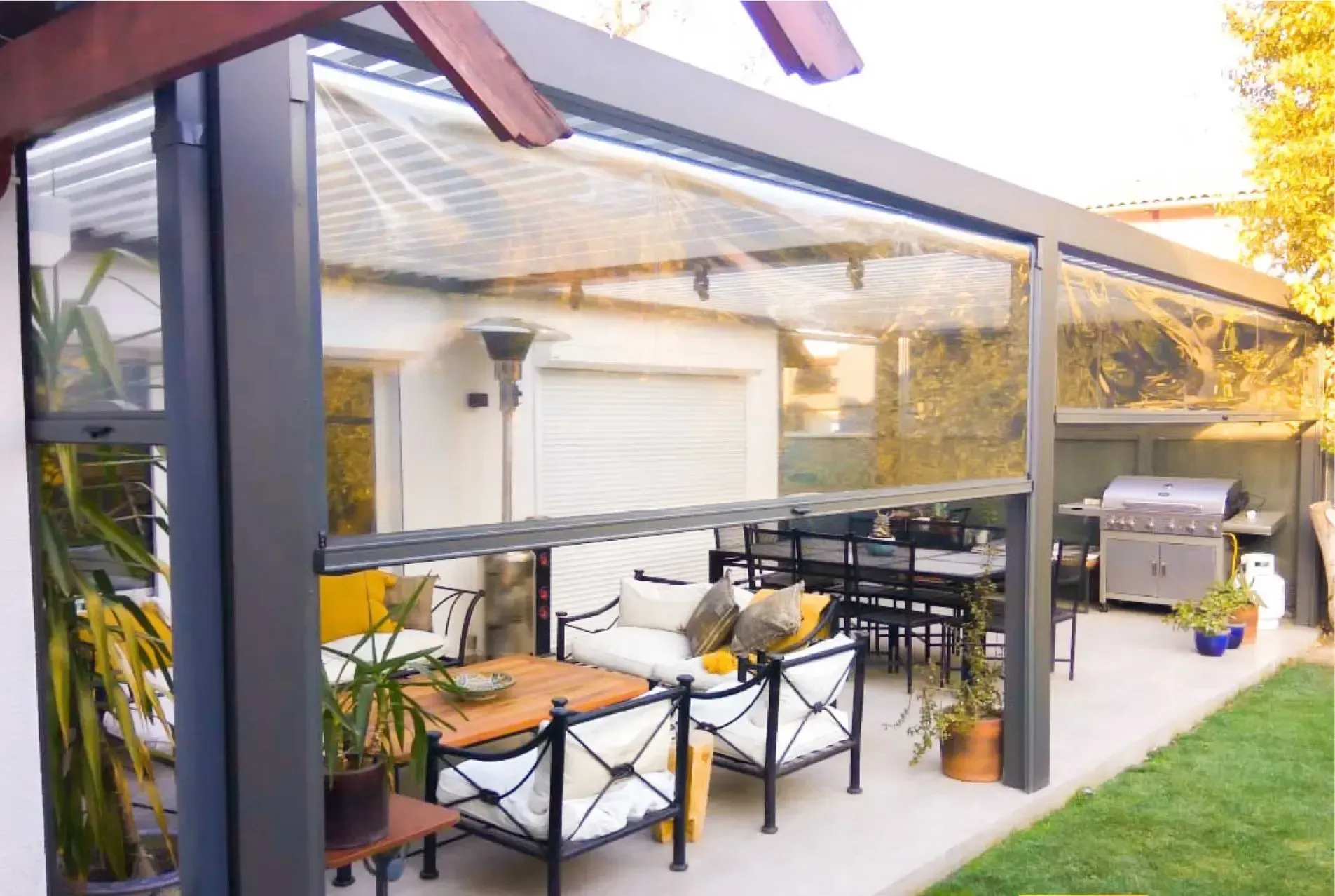 A patio with a couch , chairs , table and grill.