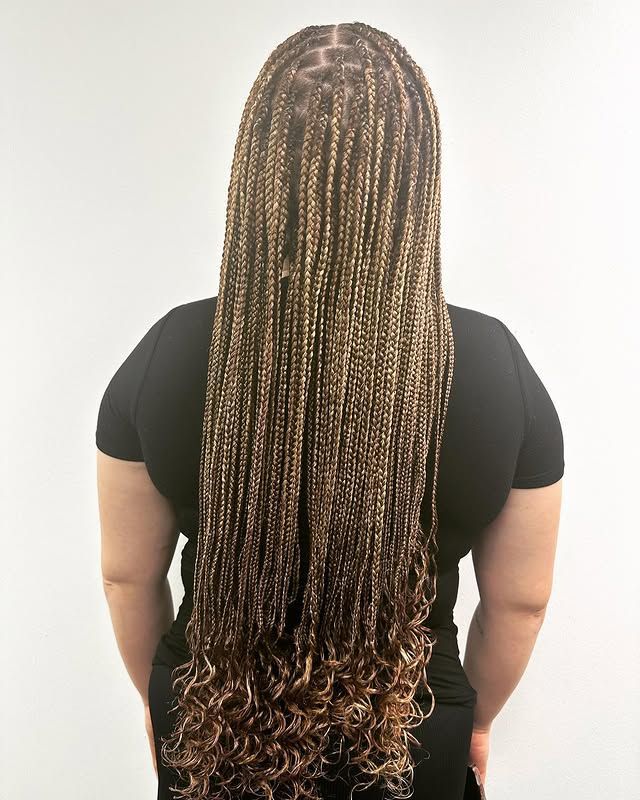 Back view of a person with long braided hair wearing a black shirt on a white background