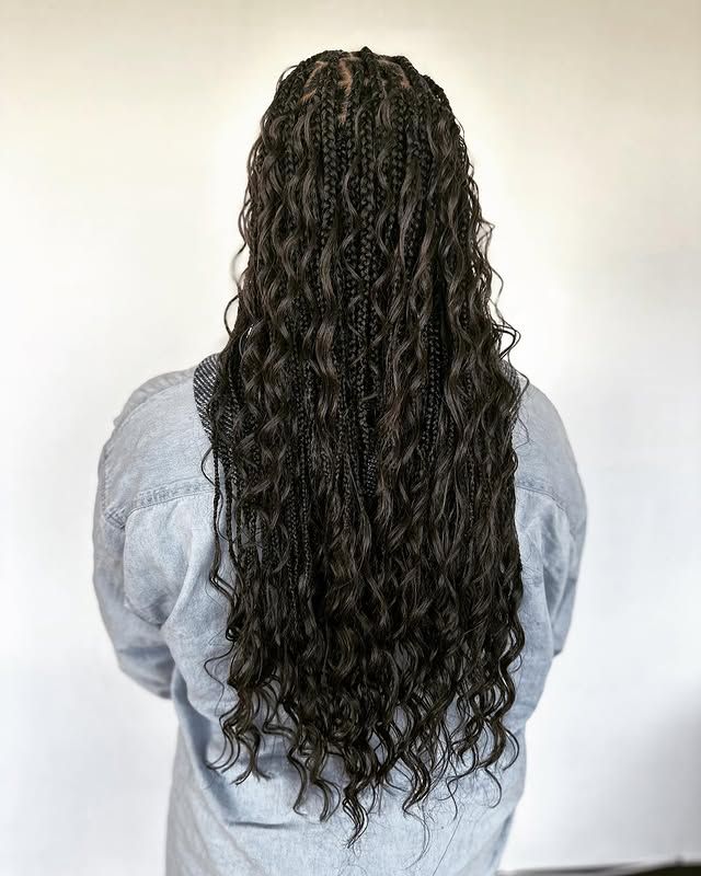 Back view of long dark curly hair cascading over a light gray shirt
