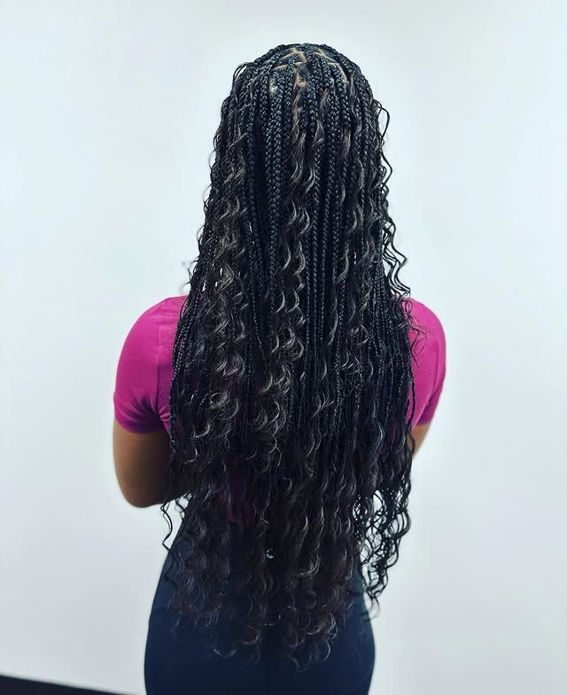 Back view of a person with long braided hair wearing a pink top and dark skirt