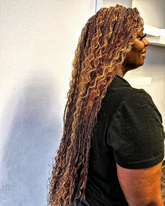 Side-view of a person with long braided hair wearing a black shirt against a light wall.