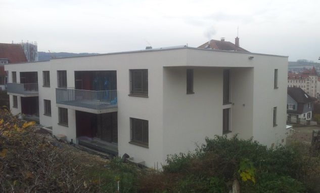 Weißes, modernes Apartmentgebäude mit Balkonen in einer nebligen Wohngegend