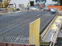 Baustelle mit Stahlbetondecke und Betonschalung, Arbeiter im Hintergrund