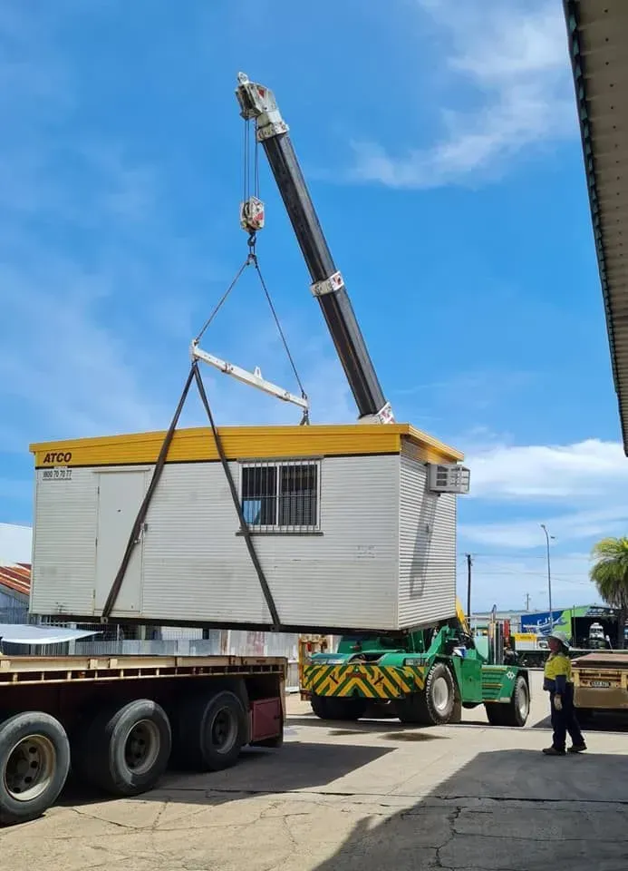 A Crane Lifting a White and Yellow Portable Building — Bell's Carrying & Crane Hire Service Pty Ltd in Port Douglas, QLD