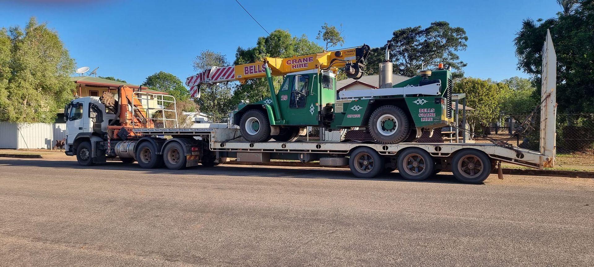 A Flatbed Truck Carrying a Green Construction — Bell's Carrying & Crane Hire Service Pty Ltd in Mareeba, QLD