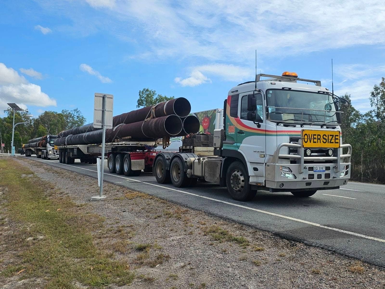 Truck Hauling Oversized Pipes on a Highway — Bell's Carrying & Crane Hire Service Pty Ltd in Bungalow, QLD