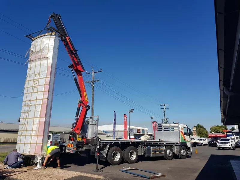 Crane lifting a tall wrapped load onto a flatbed truck — Bell's Carrying & Crane Hire Service Pty Ltd in Atherton, QLD