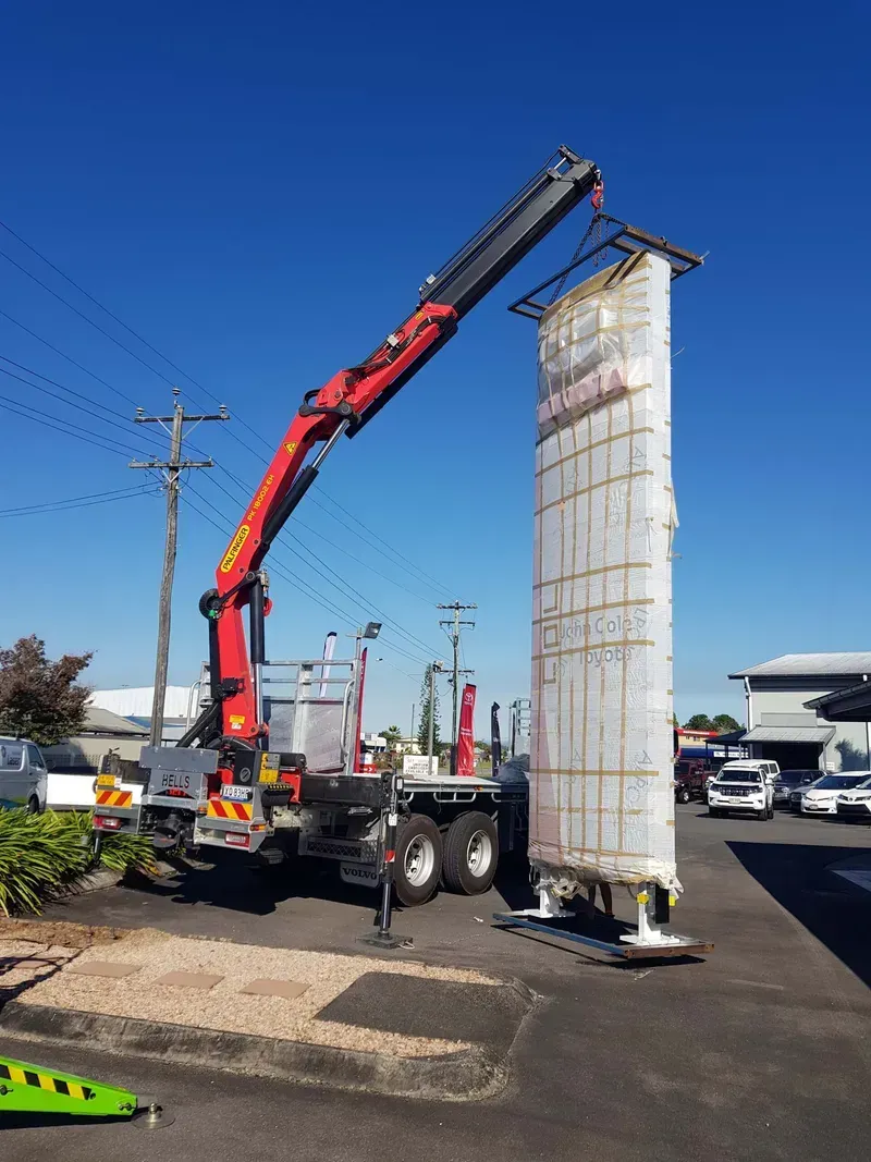 Crane lifting a wrapped white structure on a truck — Bell's Carrying & Crane Hire Service Pty Ltd in Atherton, QLD