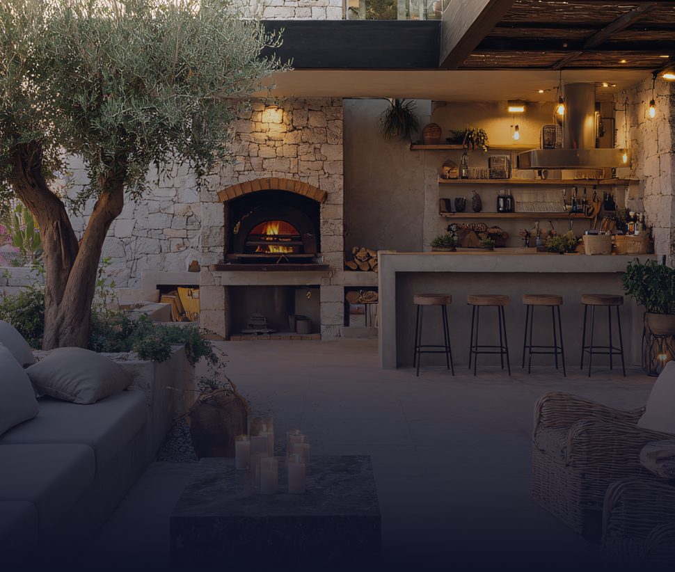 Outdoor kitchen with pizza oven, bar, and seating area, with an olive tree.