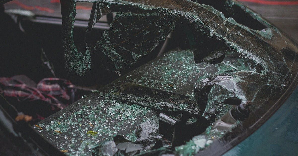 A car with a broken windshield is sitting on the ground.
