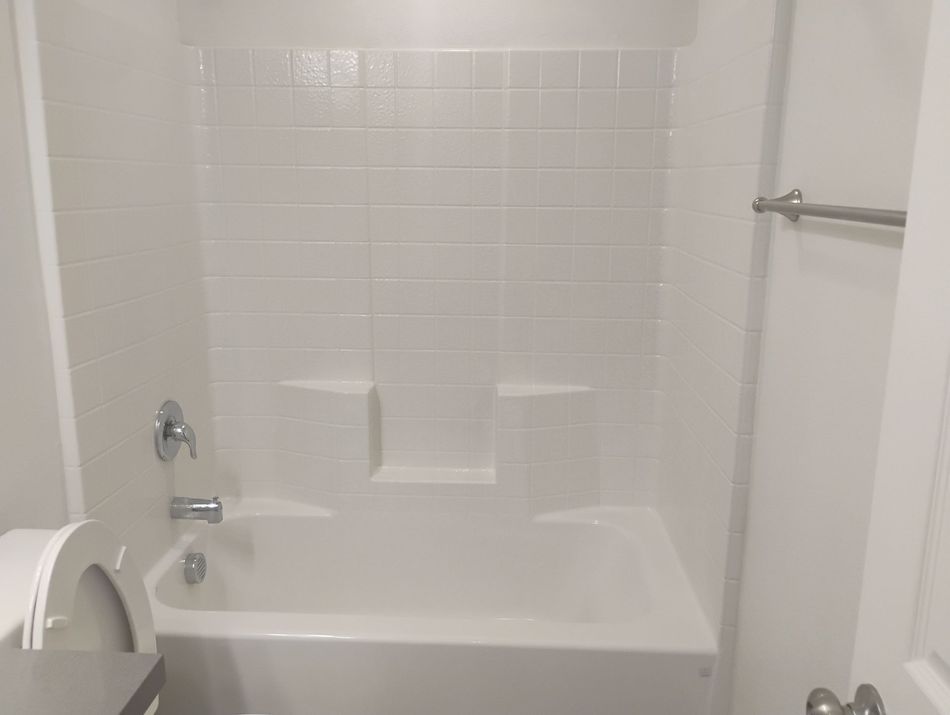 White rectangular bathroom sink with a drain and faucet, seen close up in a corner.