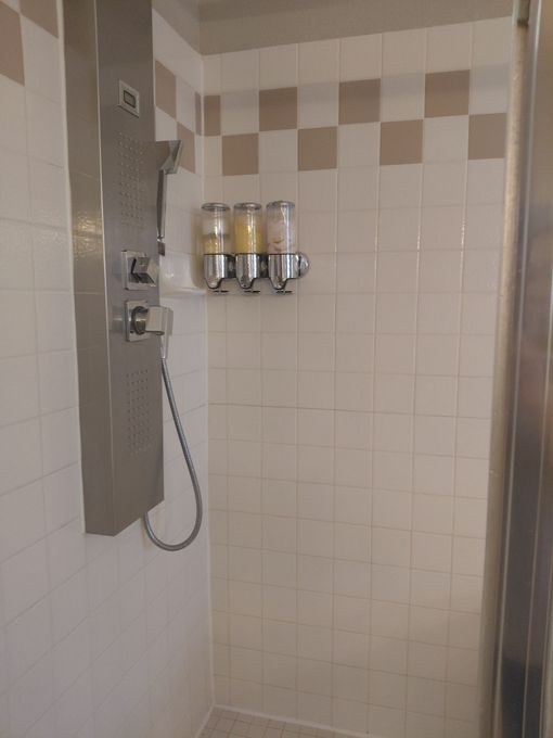 Empty white cabinet under sink with a gray wood floor and plumbing visible above