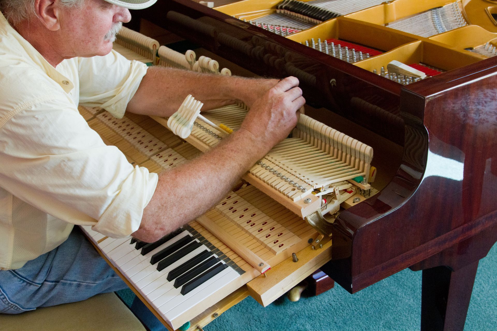 A man is kneeling on the floor working on a piano. A man is kneeling on the floor working on a piano.