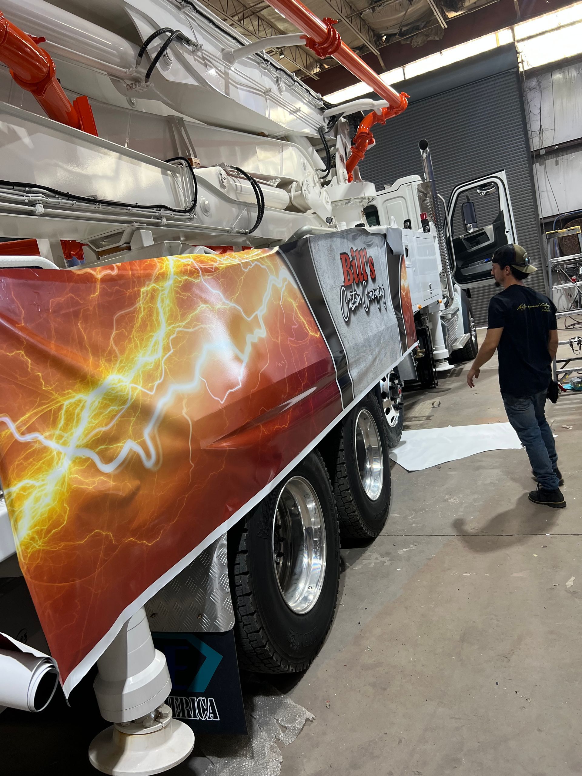 Red-and-white truck with lightning graphics at an indoor event, with a person standing beside it