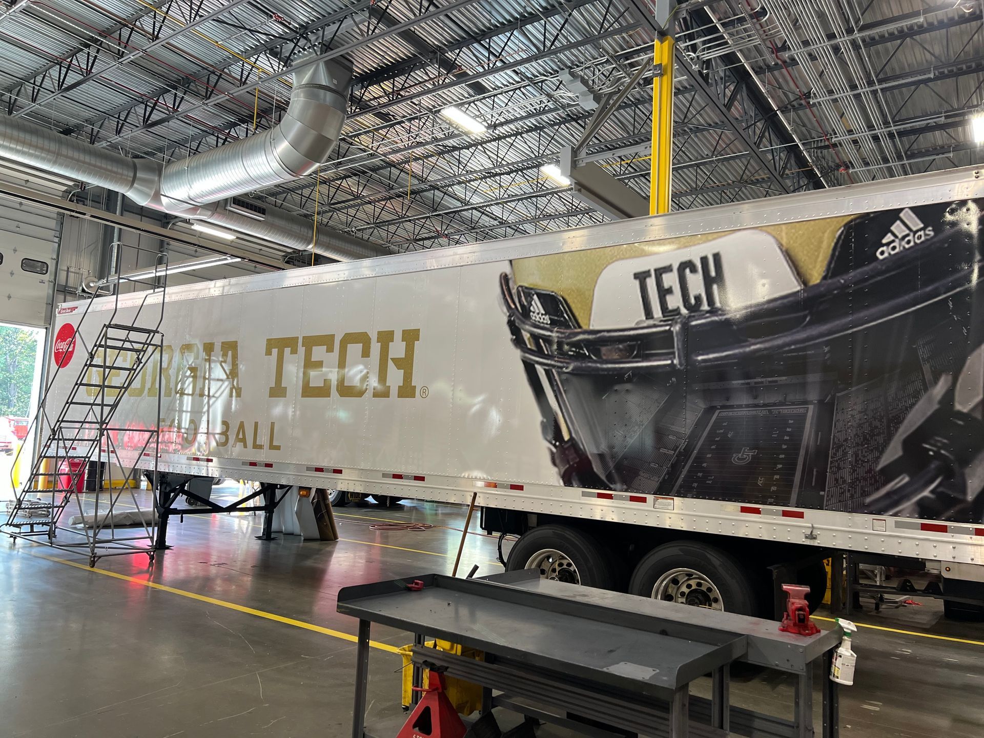 Large TECH-branded trailer inside an industrial warehouse with a black-and-white truck graphic