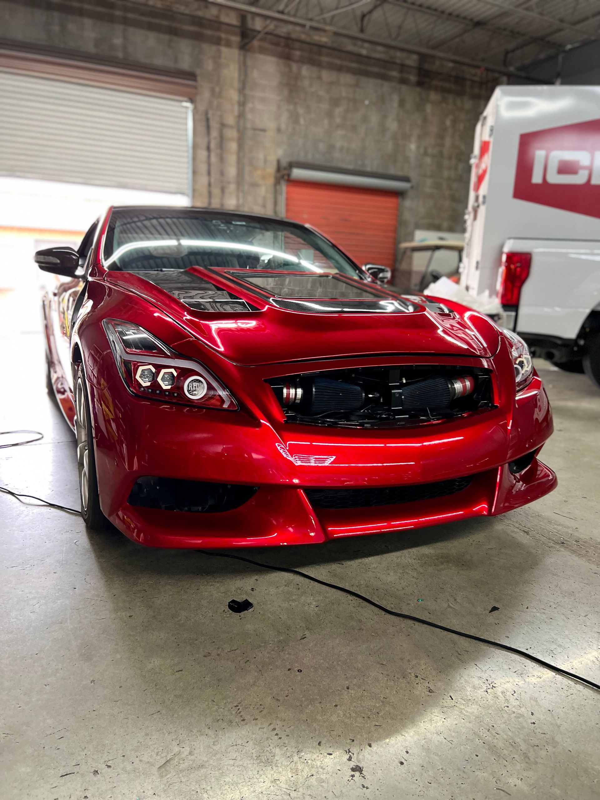 Red sports car in a garage, with a glossy hood and front bumper.
