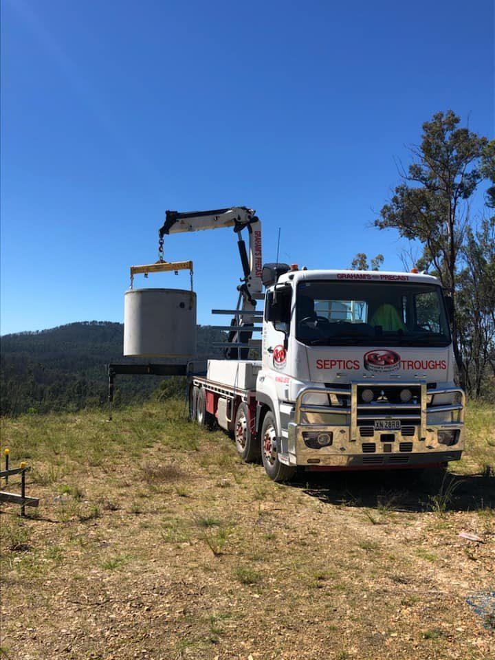 A Truck With a Crane Attached to It is Parked in a Field — Graham's Precast Concrete Products Pty Ltd in Kyogle, NSW