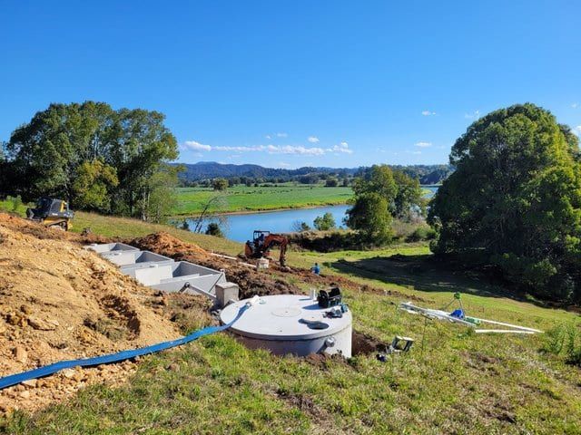 A Septic Tank Is Being Built In A Field Next To A River — Graham's Precast Concrete Products Pty Ltd in Kyogle, NSW