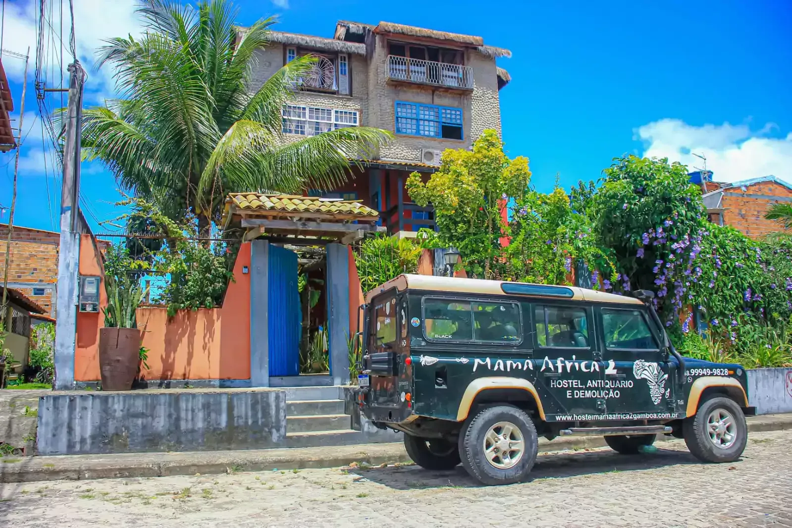 Um jipe ​​preto está estacionado em frente a um prédio.- Hostel-Mama-Africa-2